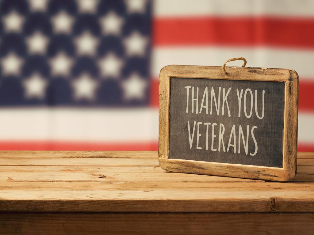 sign saing "Thank you veterans" sits on a table in front of the U.S. flag