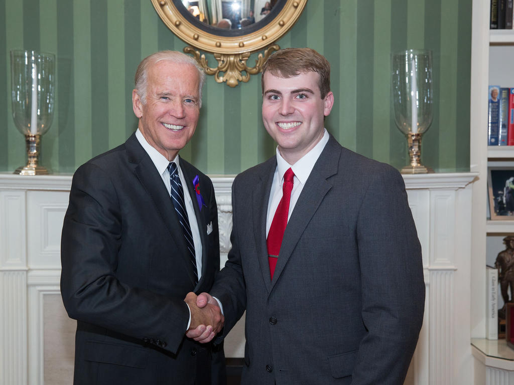 two white men shaking hands and smiling for a photo