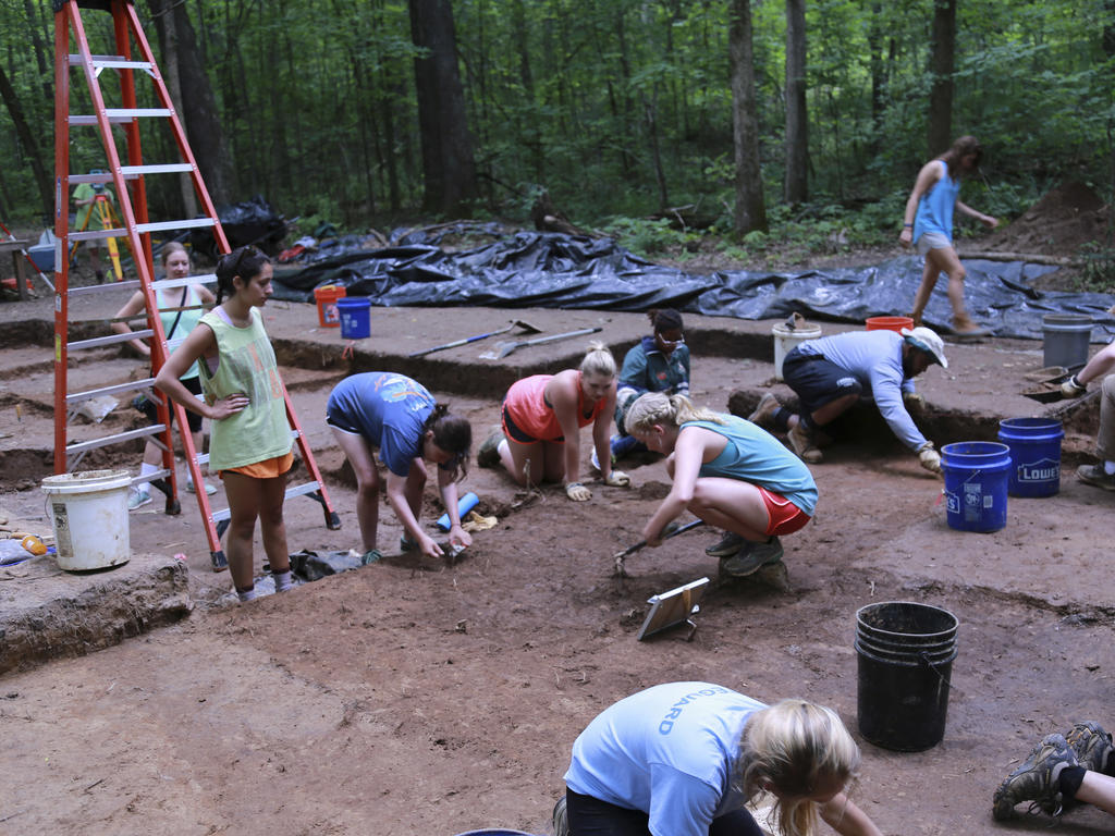 a diverse group of students participating in an archeological dig
