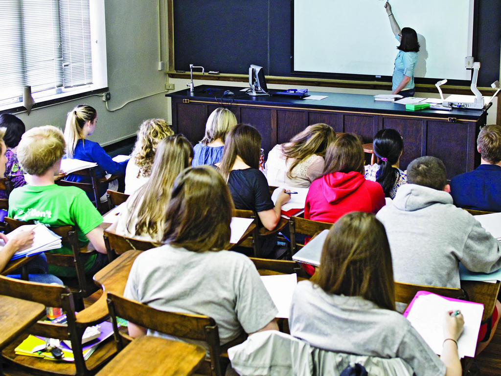 a classroom full of students taking notes while the professor lectures at the front of the room